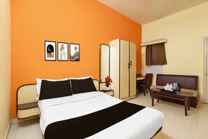 Una habitación de hotel con cama, escritorio, silla, armario y sofá.