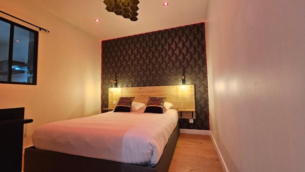 Un dormitorio moderno con cama, mesitas de noche y un original diseño geométrico en la pared.