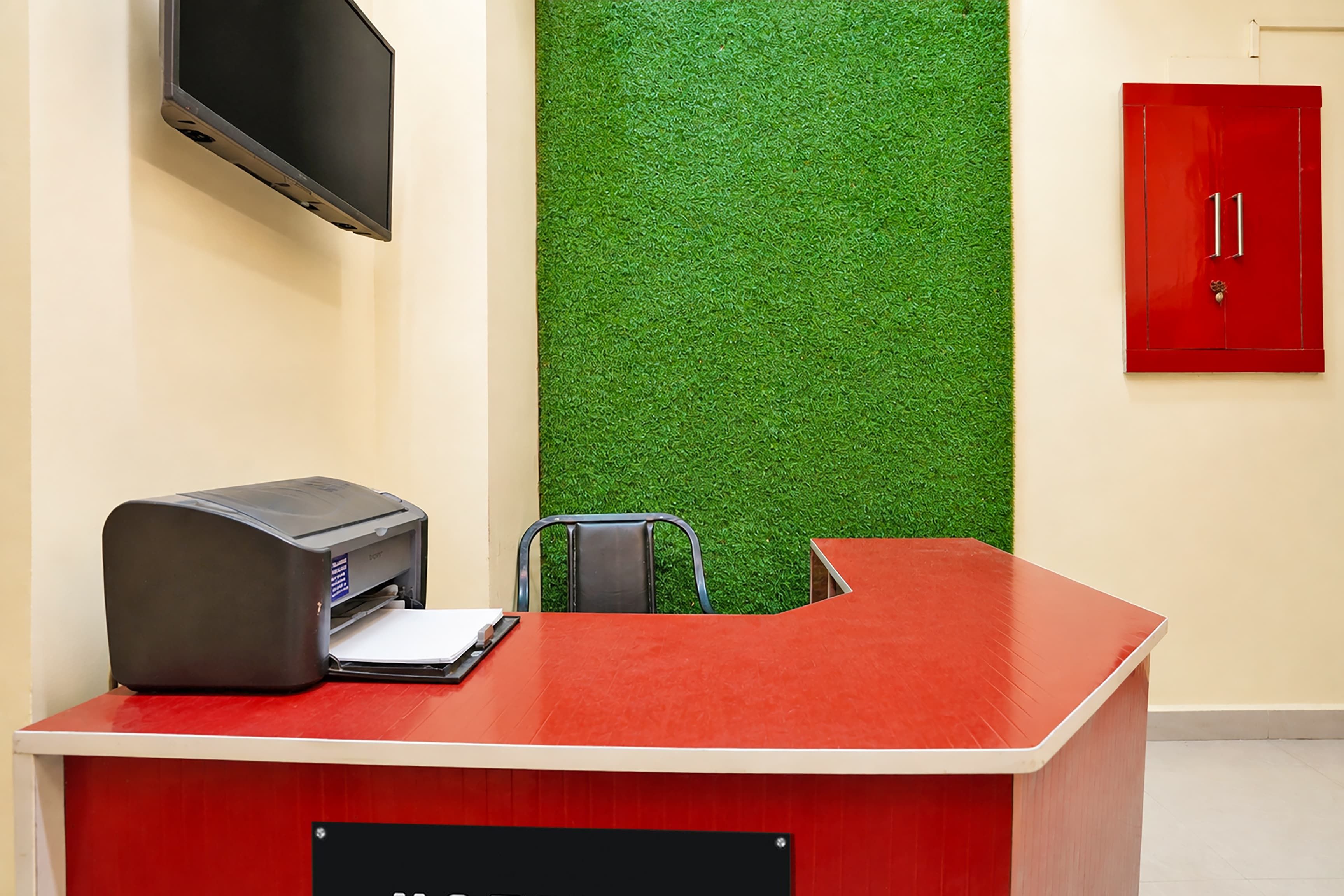 A reception desk with a printer, a chair, and a flat-screen TV mounted on the wall.