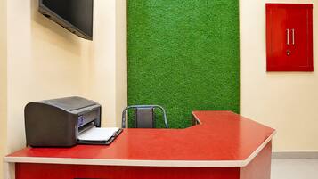 A reception desk with a printer, a chair, and a flat-screen TV mounted on the wall.