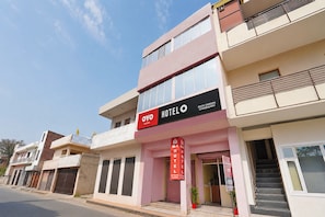 A hotel with a sign indicating 'AC Rooms Available' and a staircase leading to the entrance.