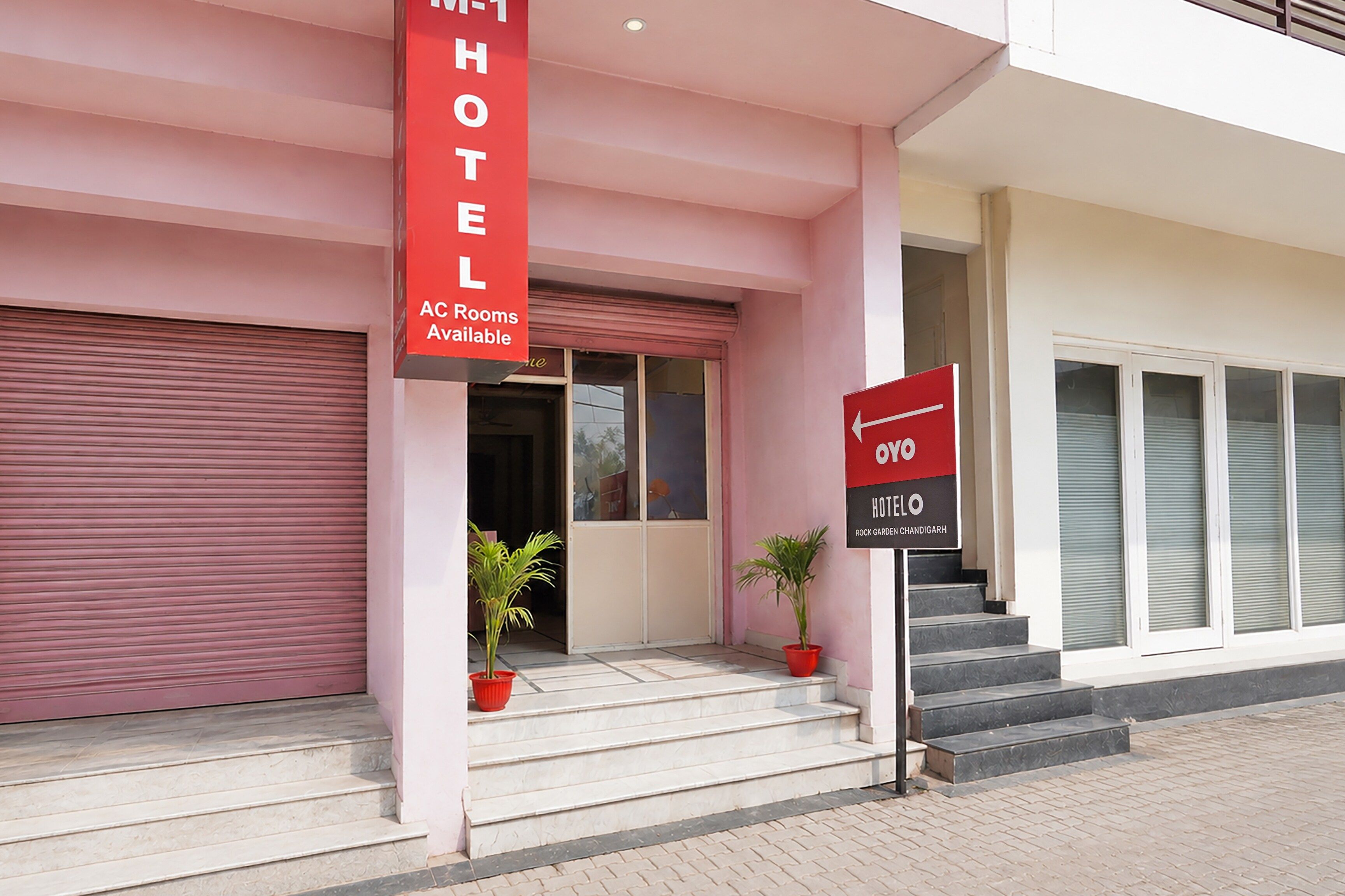 L’entrée d’un hôtel, avec une enseigne rouge indiquant la présence de chambres climatisées et un panneau indiquant la direction à suivre pour accéder à l’hôtel.