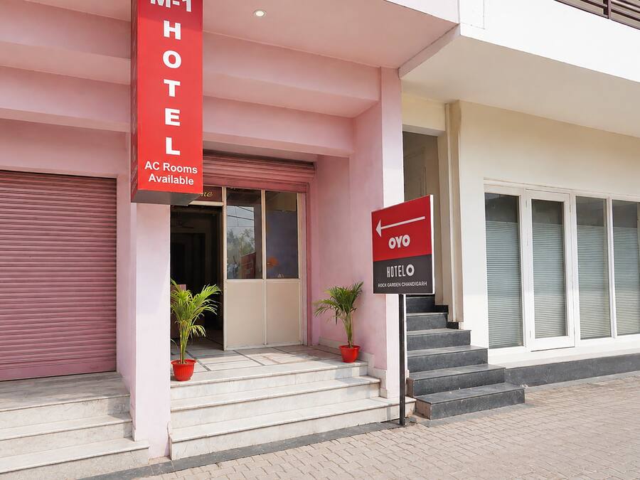 Entrada de hotel com placa vermelha indicando quartos com ar condicionado e sinalização para o hotel.
