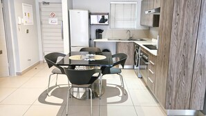 Een moderne keuken met een eettafel, stoelen, een koelkast, een wasmachine en een magnetron.