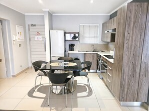 Eine moderne Küche mit Esstisch, Stühlen, Kühlschrank, Waschmaschine und Mikrowelle.