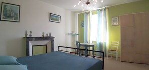A bedroom with a bed, a small table with chairs, a fireplace, and a door leading to another room. - Bed and Breakfast 'Chambre Anis' with Shared Garden and Wi-Fi (Cheillé)