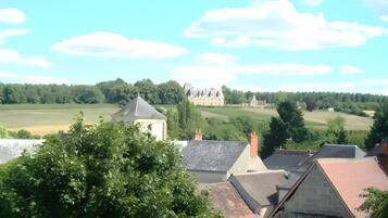 A view of a rural landscape with a large estate and several buildings with sloped roofs.