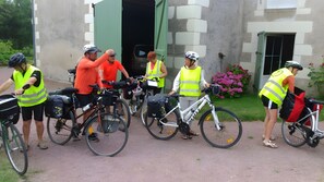 A group of cyclists with bicycles parked in front of a building with a stone facade.