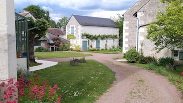 Un quartier résidentiel avec une allée pavée menant à une maison dotée d’un toit gris et de murs blancs.