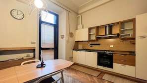 A compact kitchen with a dining table, a stove, and cabinets. - Cambiasi Apartment (Milano)