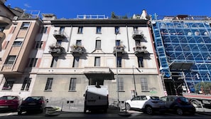 A multi-story building with balconies, a gated entrance, and a parked van. - Cambiasi Apartment (Milano)