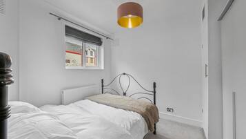 A bedroom with a bed, a window with a view, a radiator, and a pendant light.