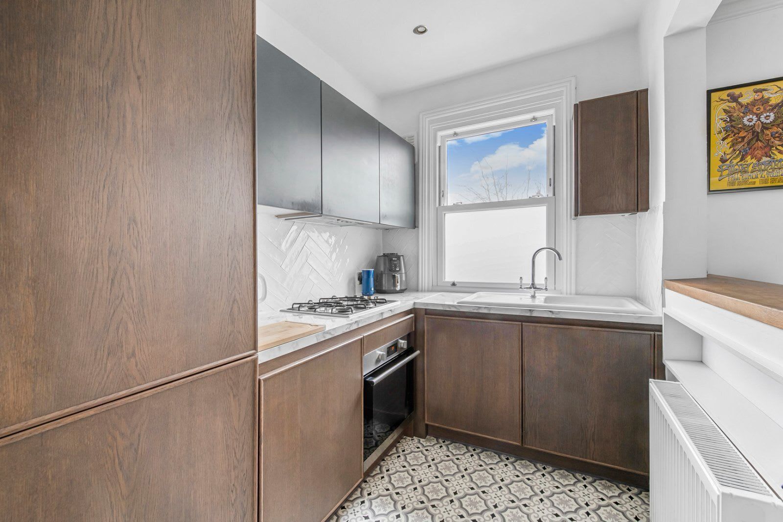 A compact kitchen with a herringbone tile backsplash, a gas stove, and a built-in oven.