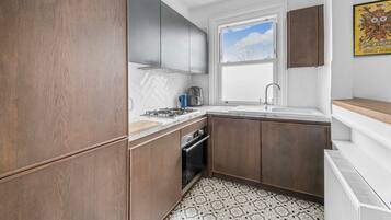 A compact kitchen with a herringbone tile backsplash, a gas stove, and a built-in oven.