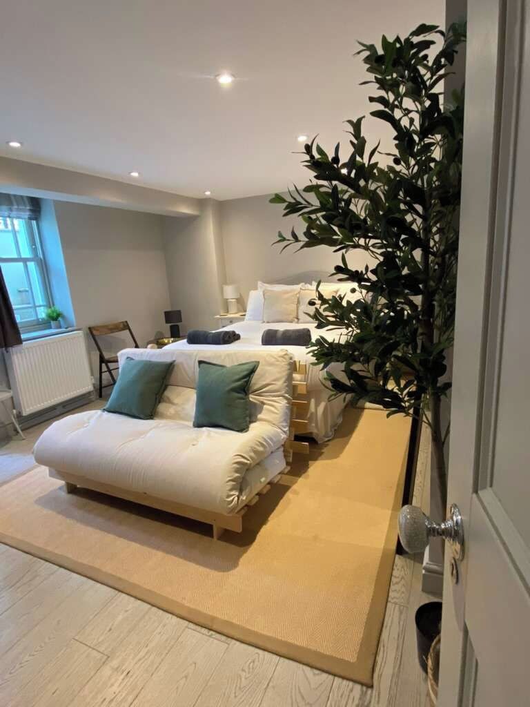 Une chambre à coucher avec un lit, une table de chevet, une chaise et une plante en pot.