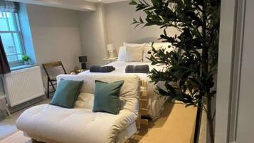Une chambre à coucher avec un lit, une table de chevet, une chaise et une plante en pot.