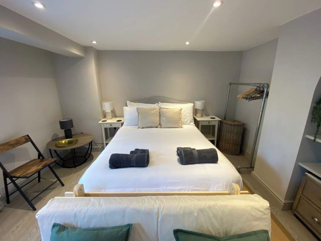 Una camera d'albergo con un letto, comodini, una sedia, uno specchio e un armadio.