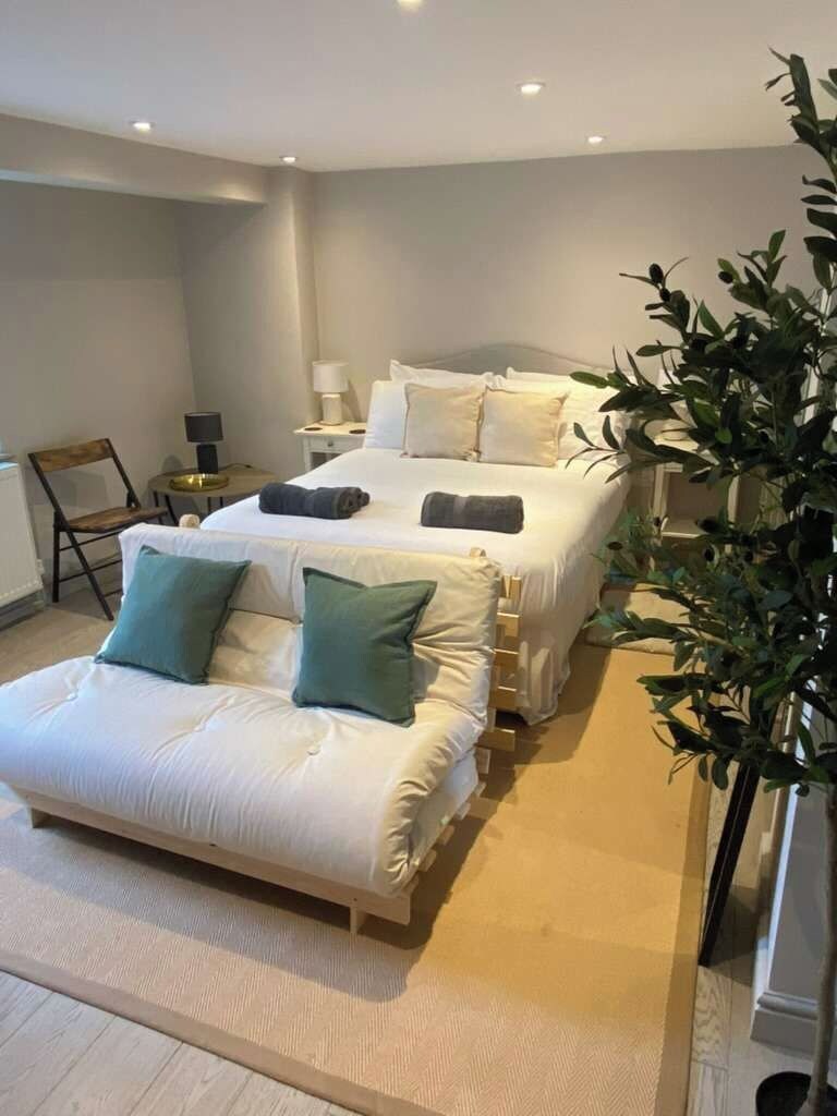 A hotel room with two beds, a sofa, a chair, and a small table.