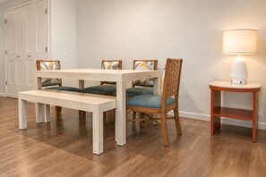 Un coin repas avec une table et des chaises en bois, un banc, une lampe et une porte.