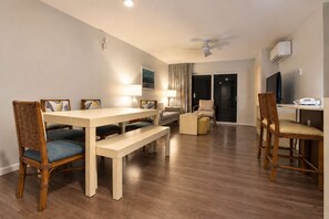 A hotel room with a dining area, a sofa, a television, and a balcony. - 3x2BR ¼ mi to Kam 1 Beach, Pool, Hot Tub, Gym, BBQ (Kihei)