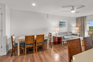 Ein modernes Wohnzimmer mit Essbereich, einer Couch und einem Deckenventilator.