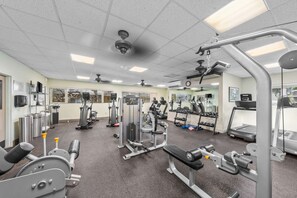 Ein Fitnessstudio mit verschiedenen Trainingsgeräten, darunter Laufbänder, Kraftgeräte und Kurzhanteln.