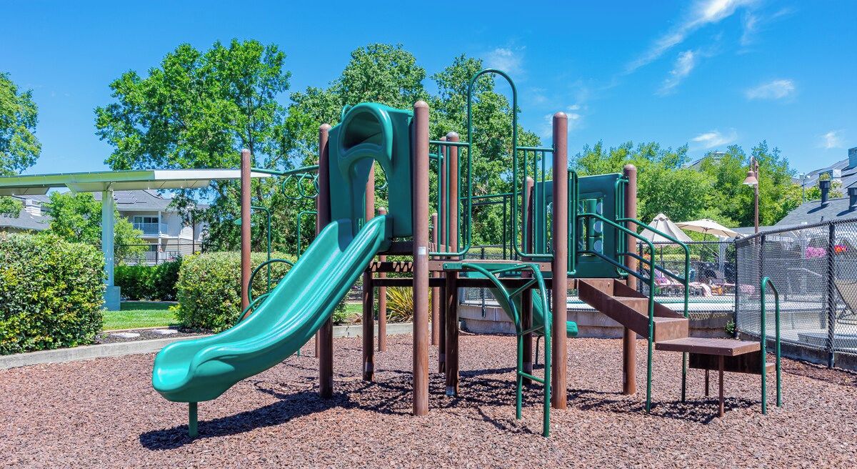 A playground with a slide, climbing structures, and a fenced area.