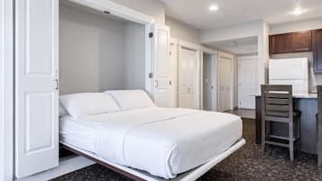 Ein Schlafzimmer mit einem Bett, einem Schreibtisch und einem Stuhl. Es gibt Türen zu anderen Räumen.