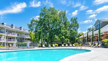 A swimming pool with a clear blue sky, surrounded by multi-story buildings with balconies.