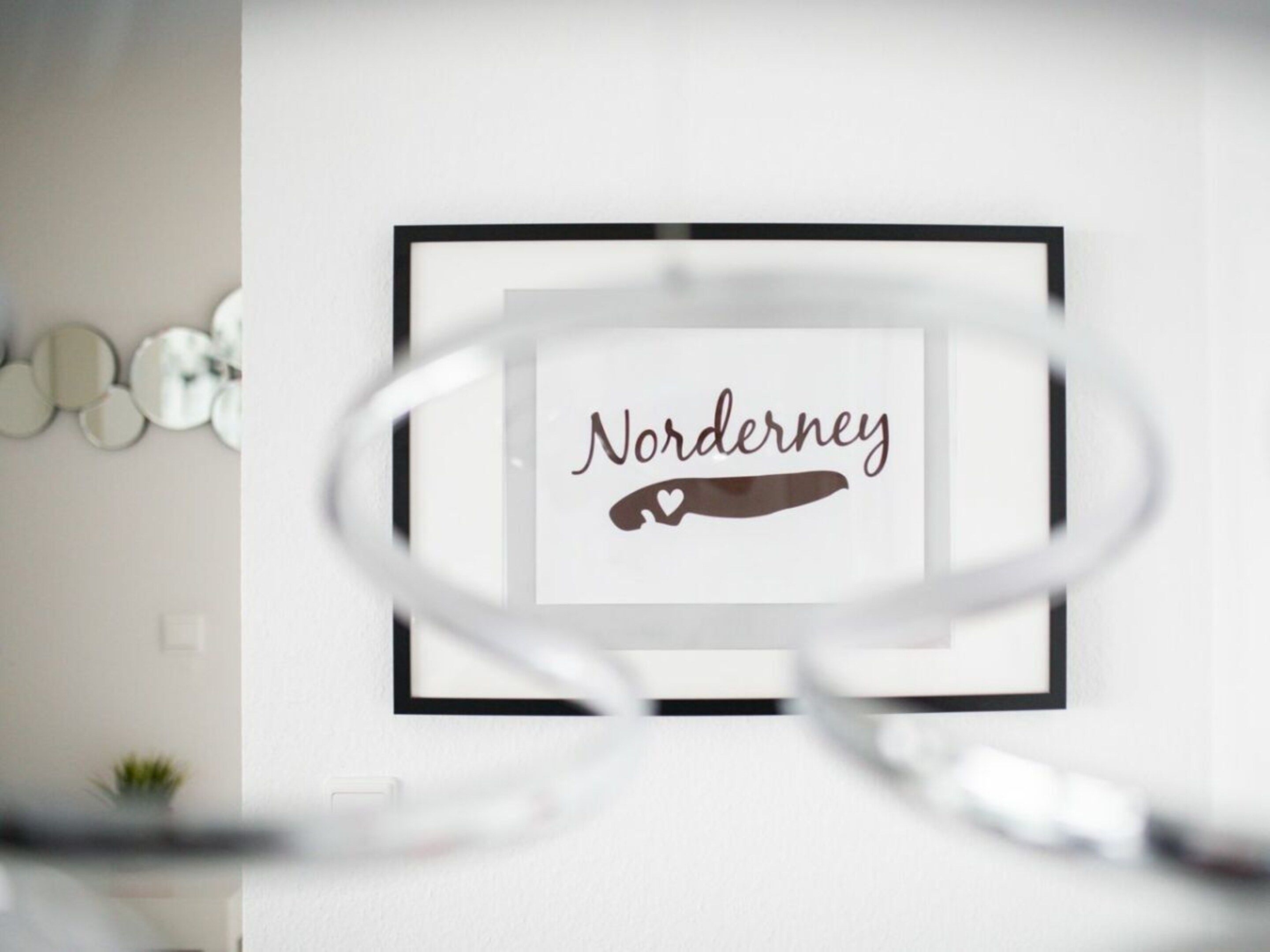 Ein gerahmtes Schild mit dem Schriftzug 'Norderney' und einem Herz-Symbol.