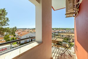 Un balcon donnant sur un quartier résidentiel, avec une rambarde en métal et une prise de courant.