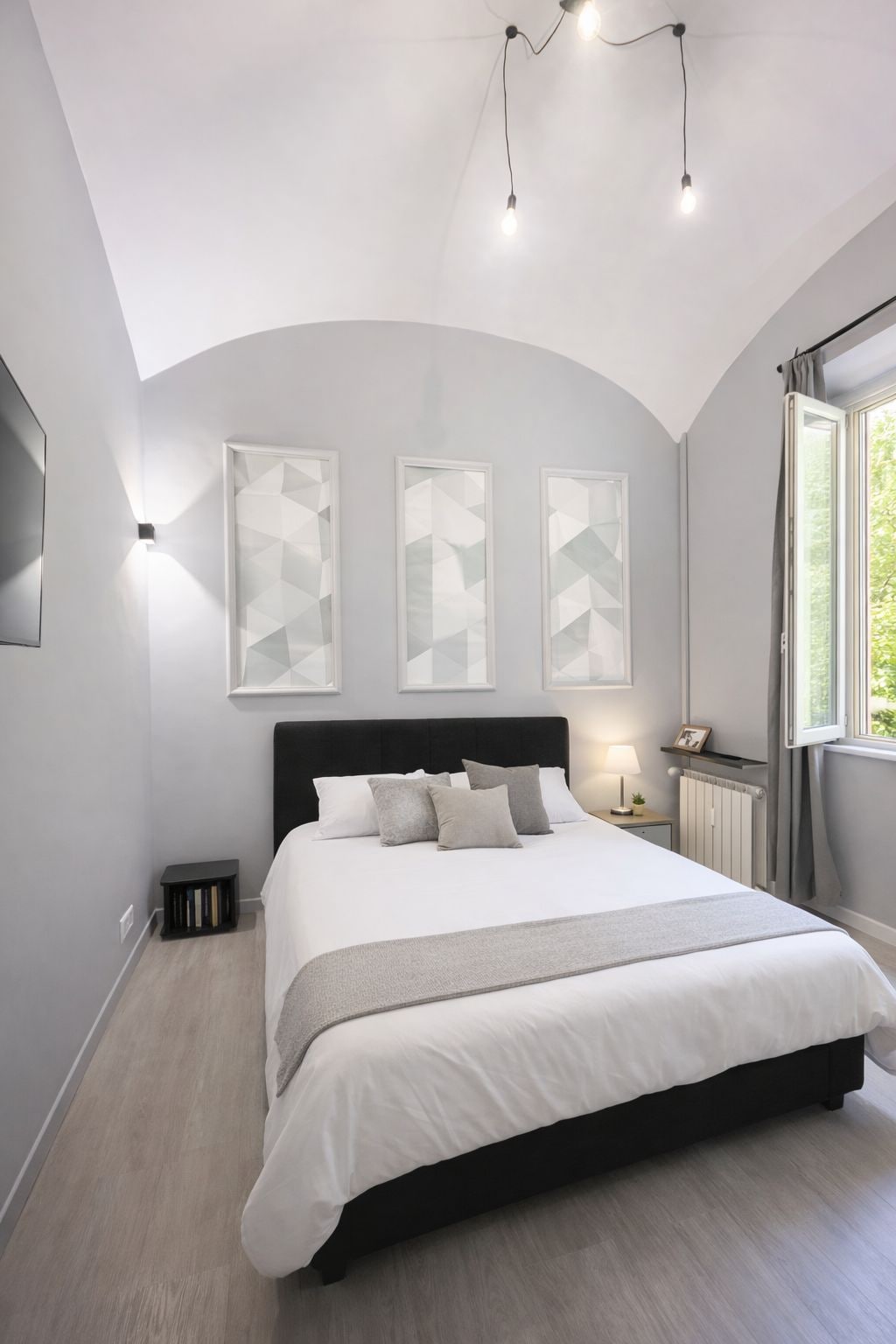 Un dormitorio con una cama grande, cabecera, mesitas de noche y una ventana con cortinas.