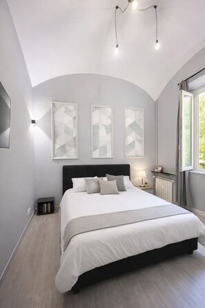 Une chambre à coucher avec un grand lit, une tête de lit, des tables de chevet et une fenêtre avec des rideaux.