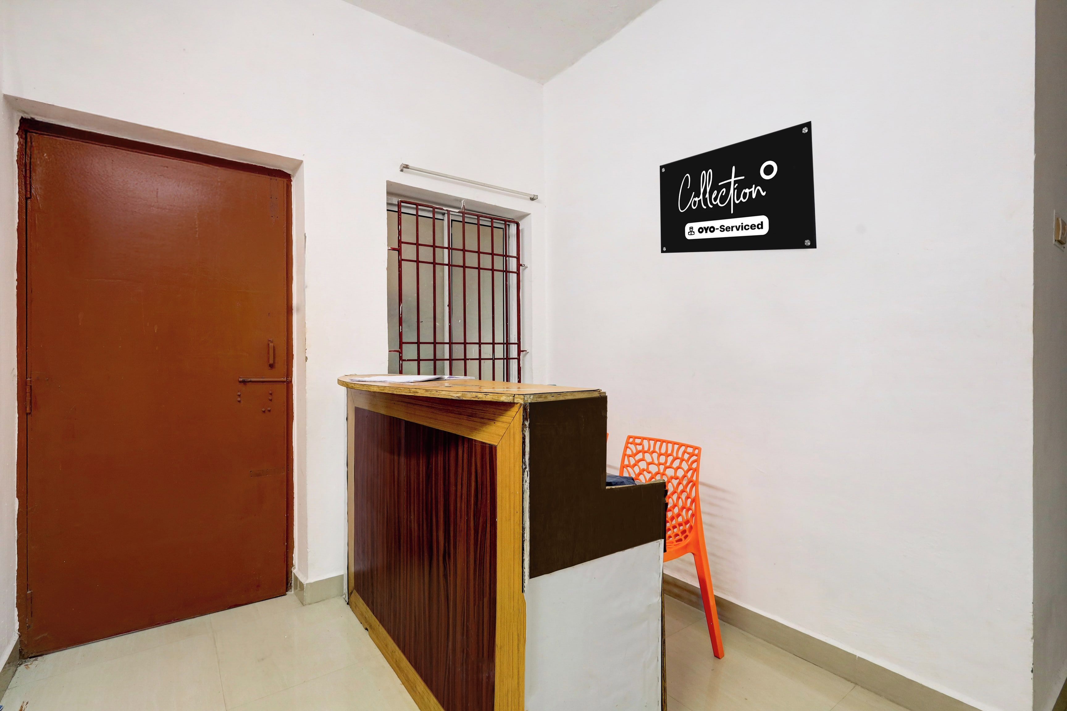A room with a wooden desk, a chair, a door, and a window with metal bars.