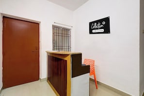 Una habitación con escritorio de madera, una silla, una puerta y una ventana con barrotes.