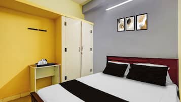 Una habitación de hotel con cama, mesita de noche, armario y una obra de arte en la pared.