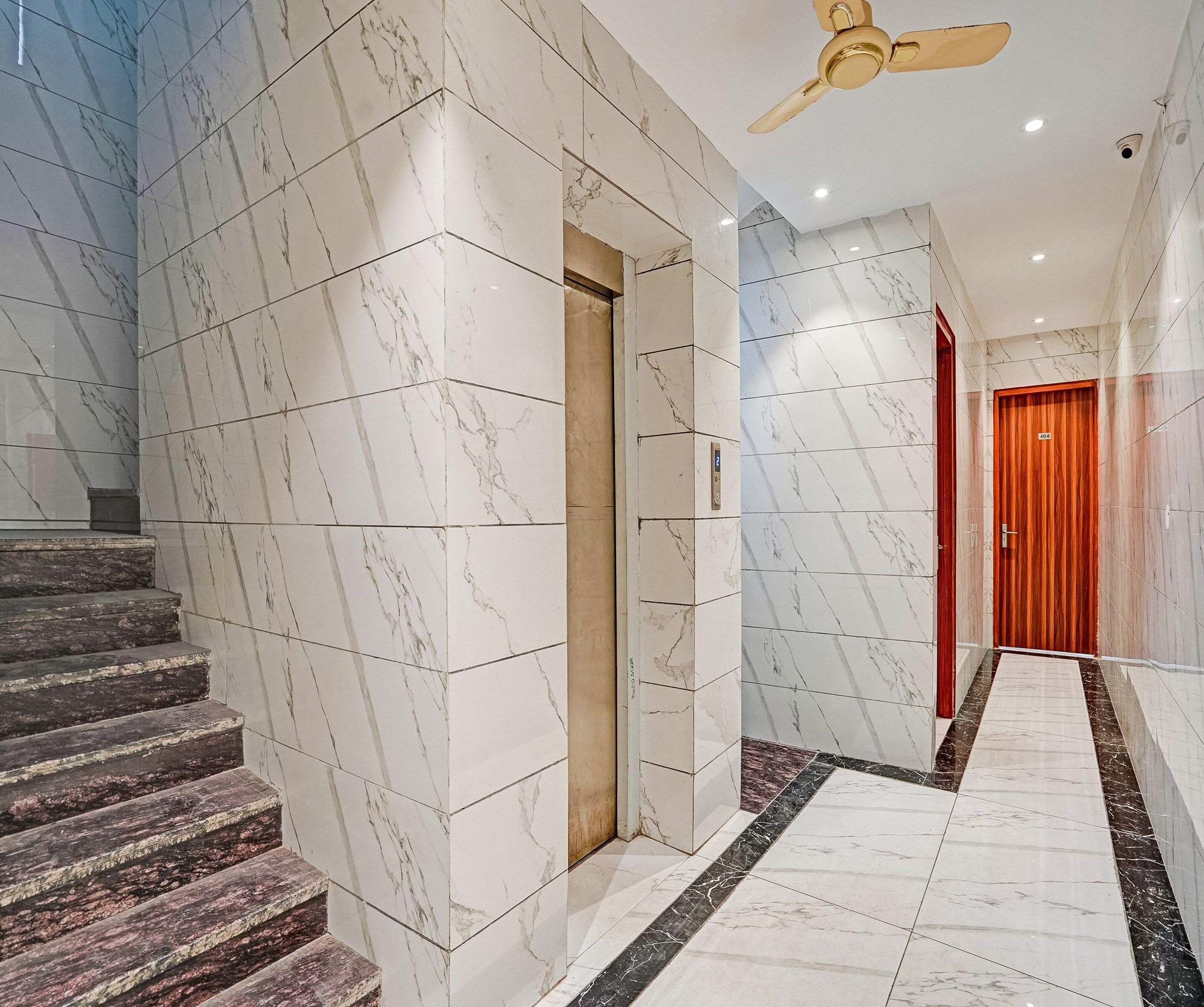 Un pasillo de hotel con piso de mármol, una puerta de madera y un ventilador de techo.