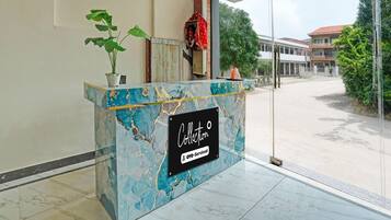 A reception desk with a marble top, a potted plant, and a sign indicating 'Collection' and 'OYO-Serviced'.