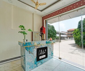 A reception desk with a marble top, a potted plant, and a sign indicating 'Collection' and 'OYO-Serviced'. - Luxury Hotel Retirement Home (Kalka)