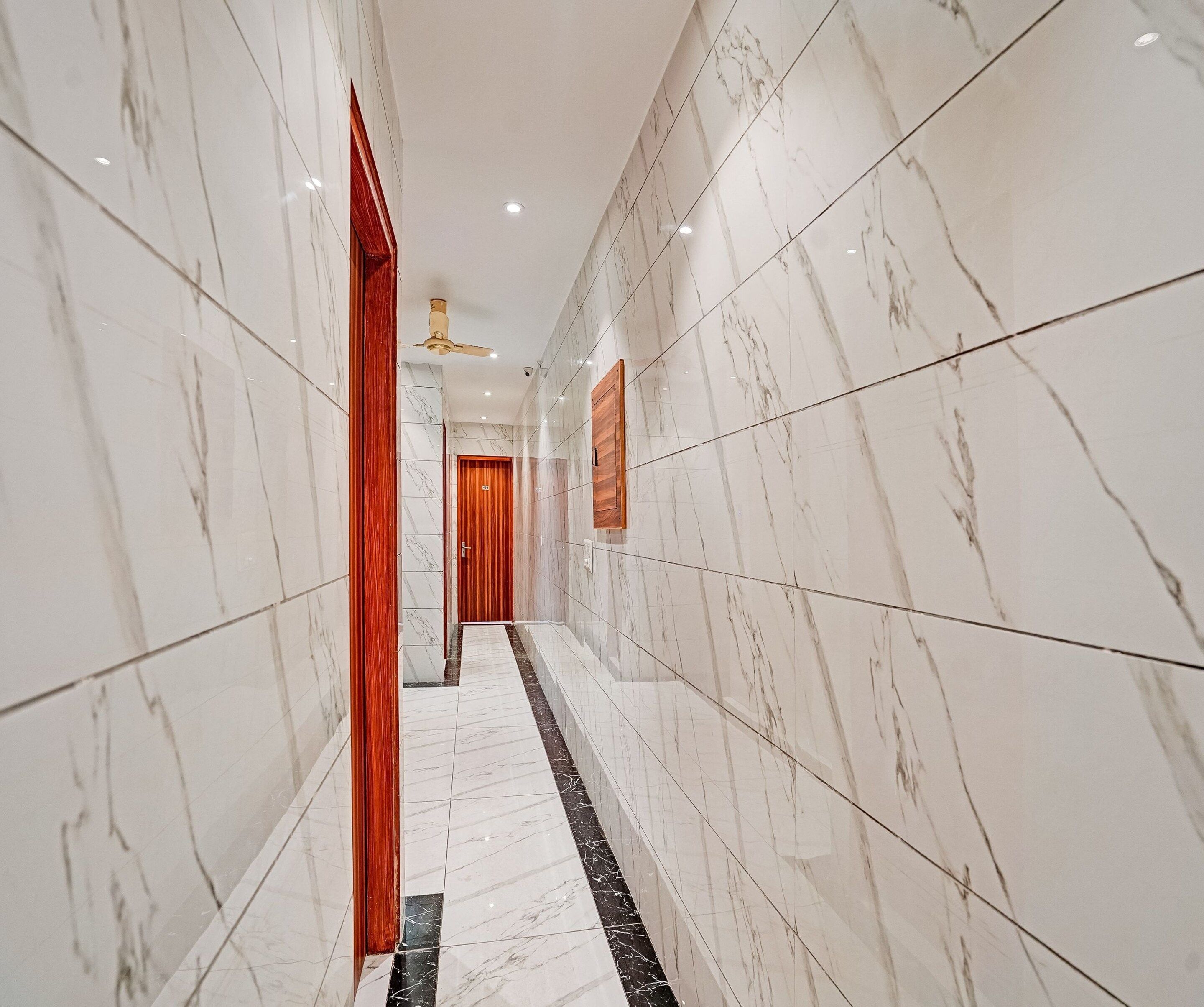 A corridor with marble walls and a black and white tiled floor.