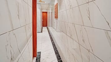 A corridor with marble walls and a black and white tiled floor.