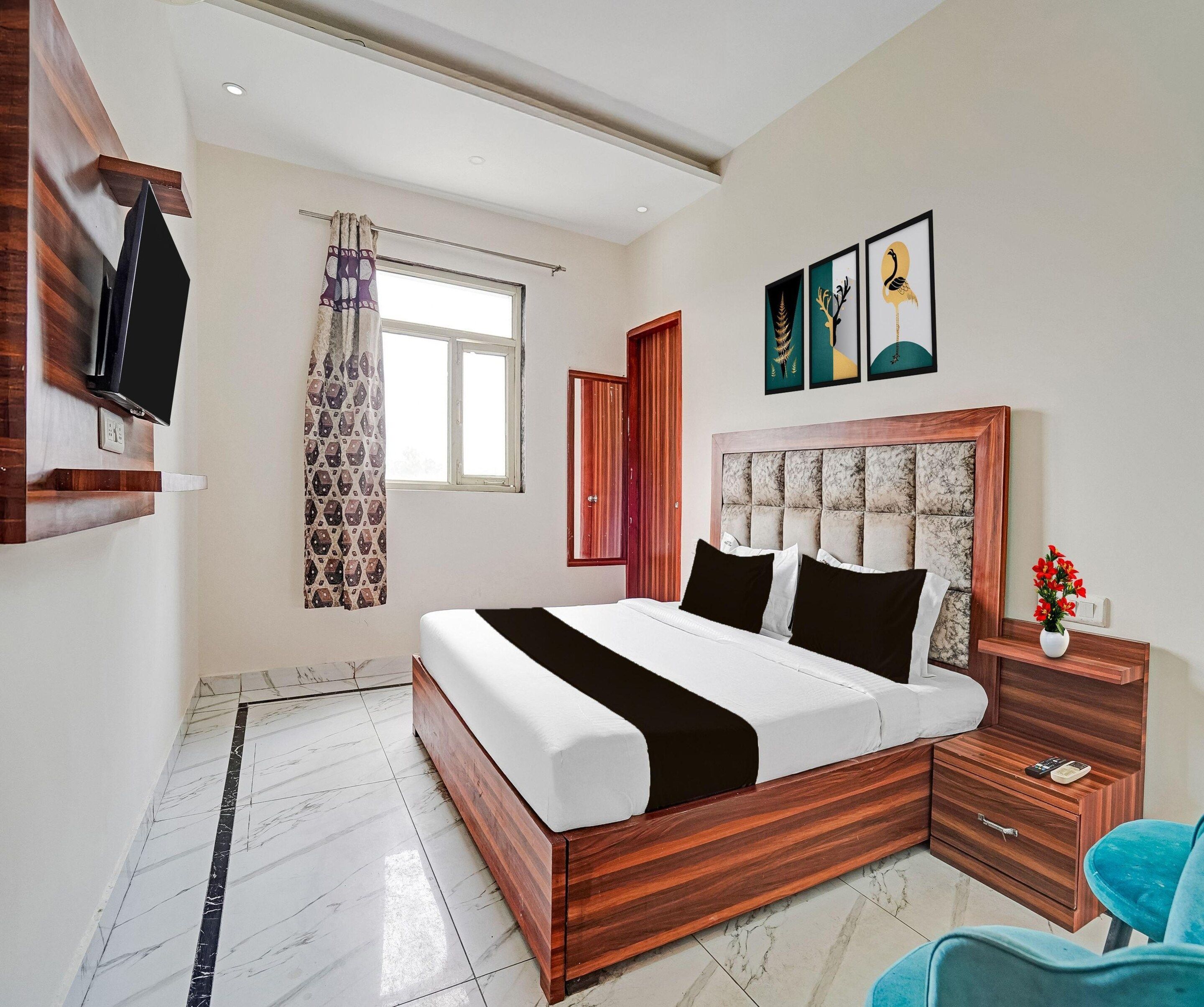 Un dormitorio moderno con estructura de cama de madera, una mesita de noche con un florero y un televisor de pantalla plana montado en la pared.