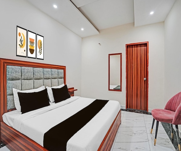A hotel room with a bed, a wooden door, a mirror, and a chair.