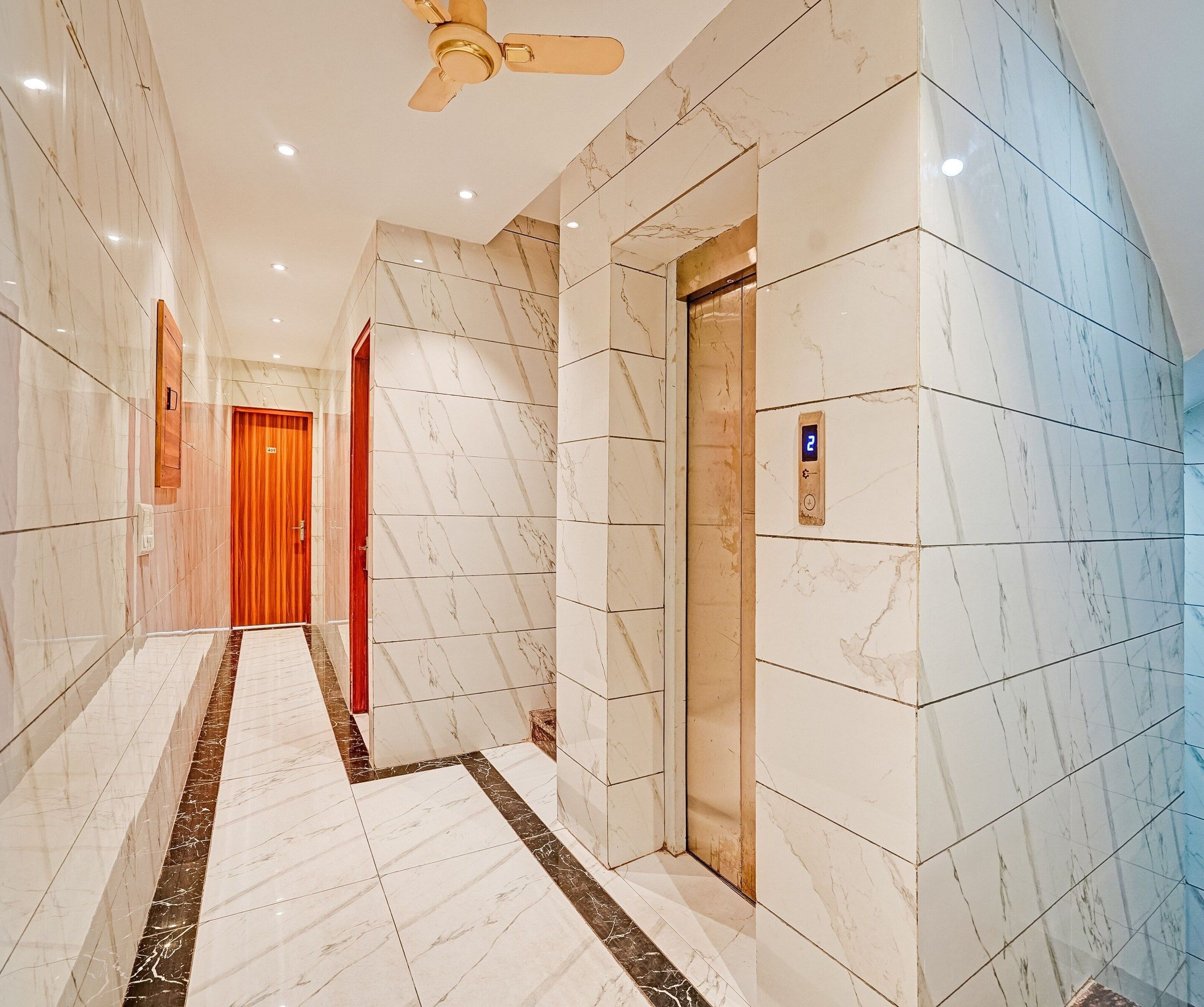 A modern elevator with a digital display, marble walls, and a wooden door.