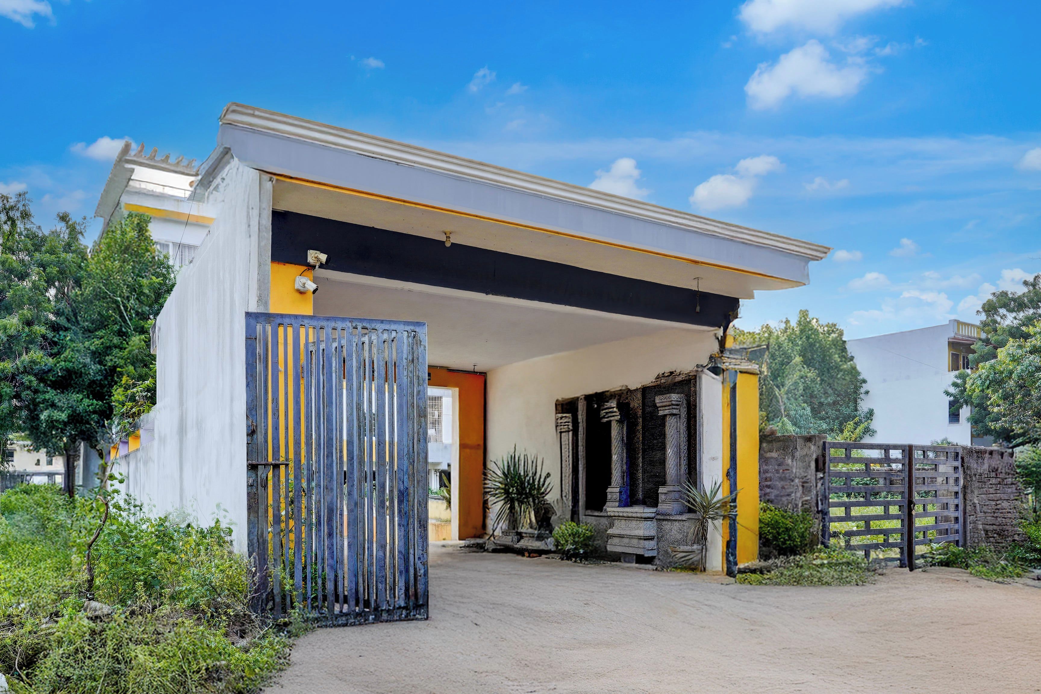 A modern house with a covered entrance, a gated driveway, and a well-maintained garden.