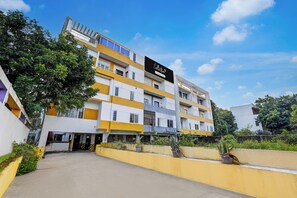 A multi-story hotel building with a yellow and white facade, a signboard, and a clear sky.