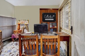 A room with a dining table, chairs, a computer, and a sign that reads 'Collection Company-Serviced'.
