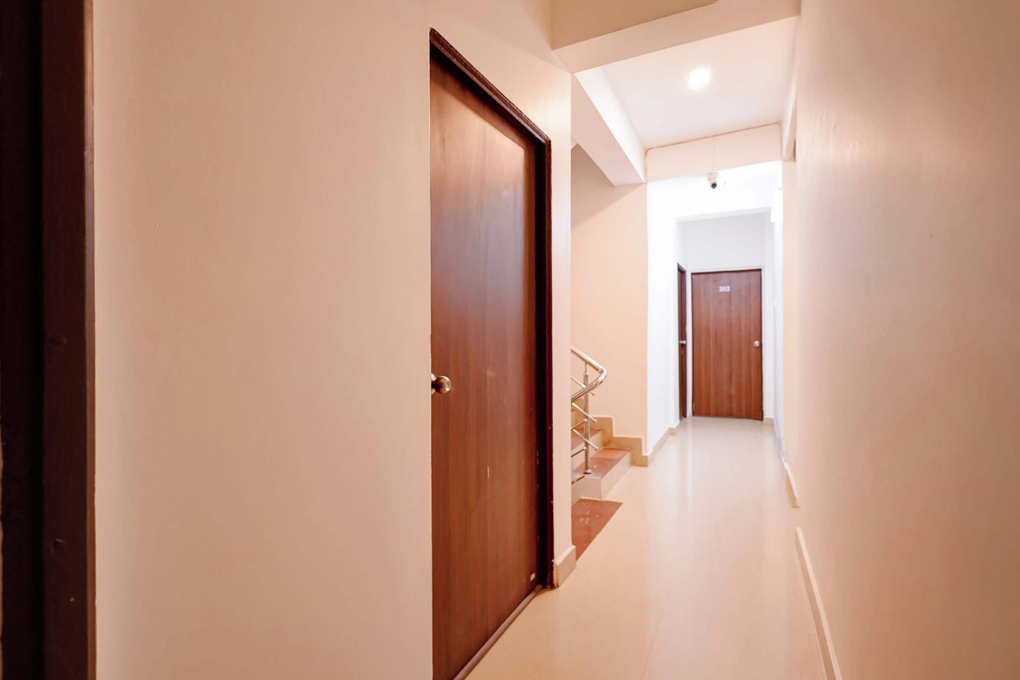 A hallway with a wooden door, a staircase, and a door with the number 202.