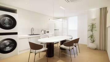 A modern kitchen with a central island, white cabinetry, and a dining area with chairs.