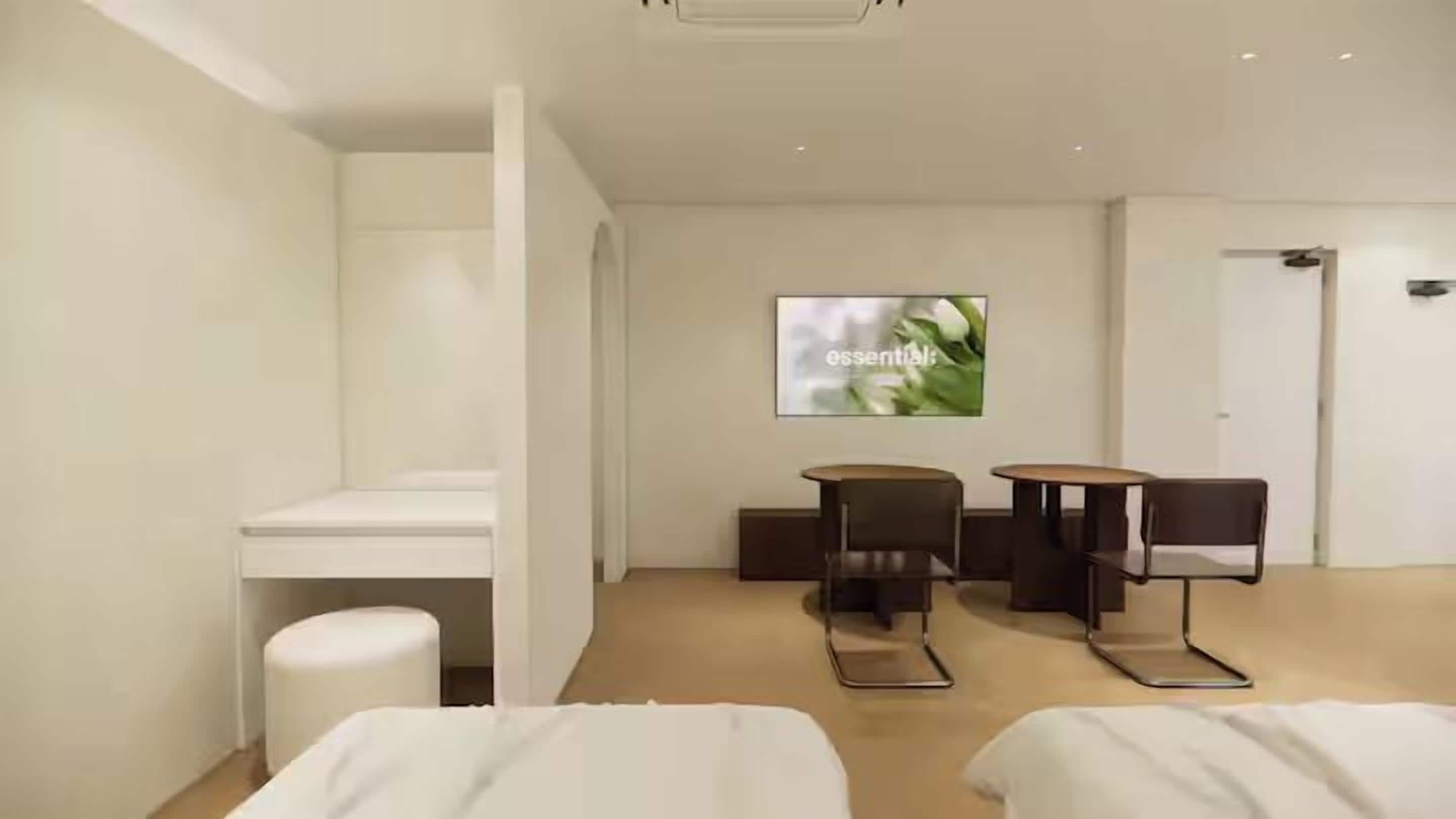 A hotel room with a bed, a desk, a chair, a TV, and a small table.